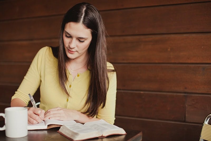 A Christian woman writing in a journal as she studies the Bible