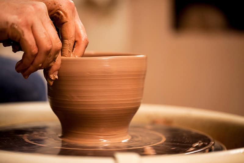 a potter's hands shaping clay into a pot as a representation of Christians being God's masterpiece in progress