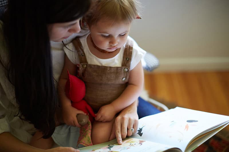 A Christian mom practicing faithfulness in little things by reading a picture book to her toddler