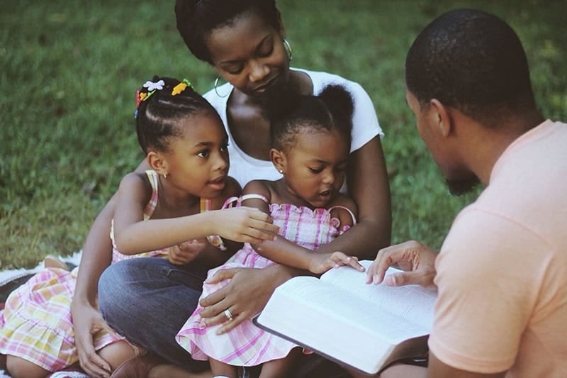 A Christian family reading the Bible together as the parents attempt to pass down your faith to the next generation