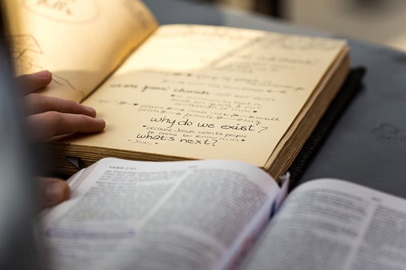 An open Bible and an open journal with notes written in it