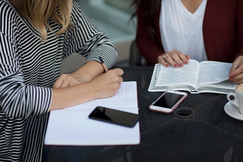 Two Christian women journaling God's faithfulness and reading the Bible