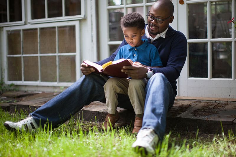 A Christian dad reading the Bible to his young son as he seeks to cultivate faith in children