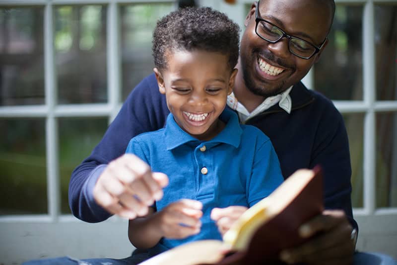 A Christian dad reading a book to his young boy as he works to cultivate faith in children