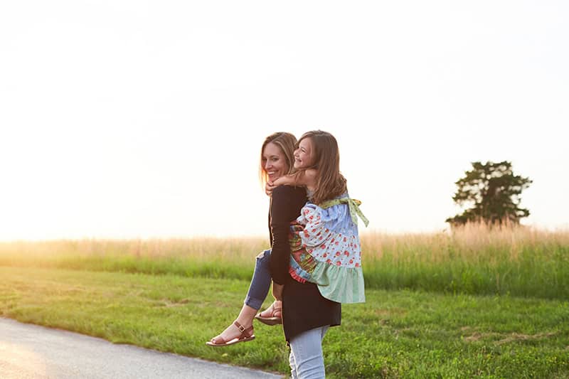 A Christian mom giving her young daughter a piggy-back ride