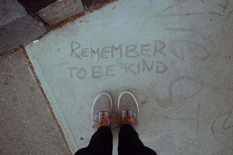A message printed into the sidewalk at someone's feet, reminding us that kindness is a way to bless the Lord