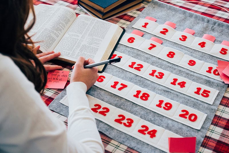 A Christian woman studying the Bible beside a felt Advent calendar