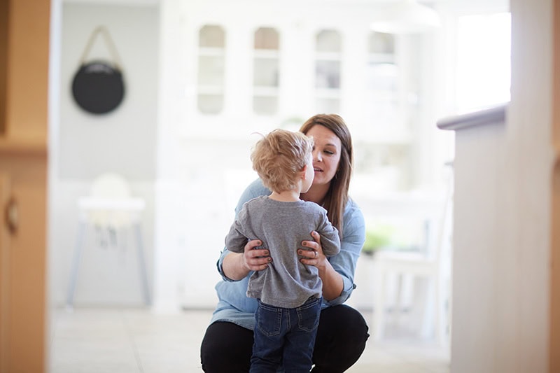 A Christian mom kneeling down to talk to her toddler about obedience and God's mercy