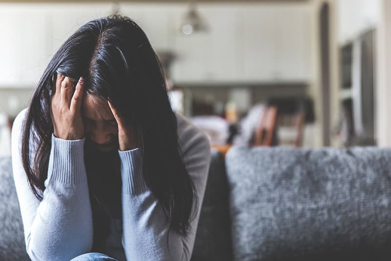 A Christian woman bowing her head in a prayer for difficult times