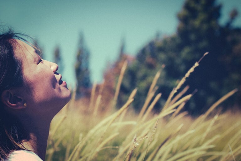 A Christian woman looking up to the sky in prayer for difficult times