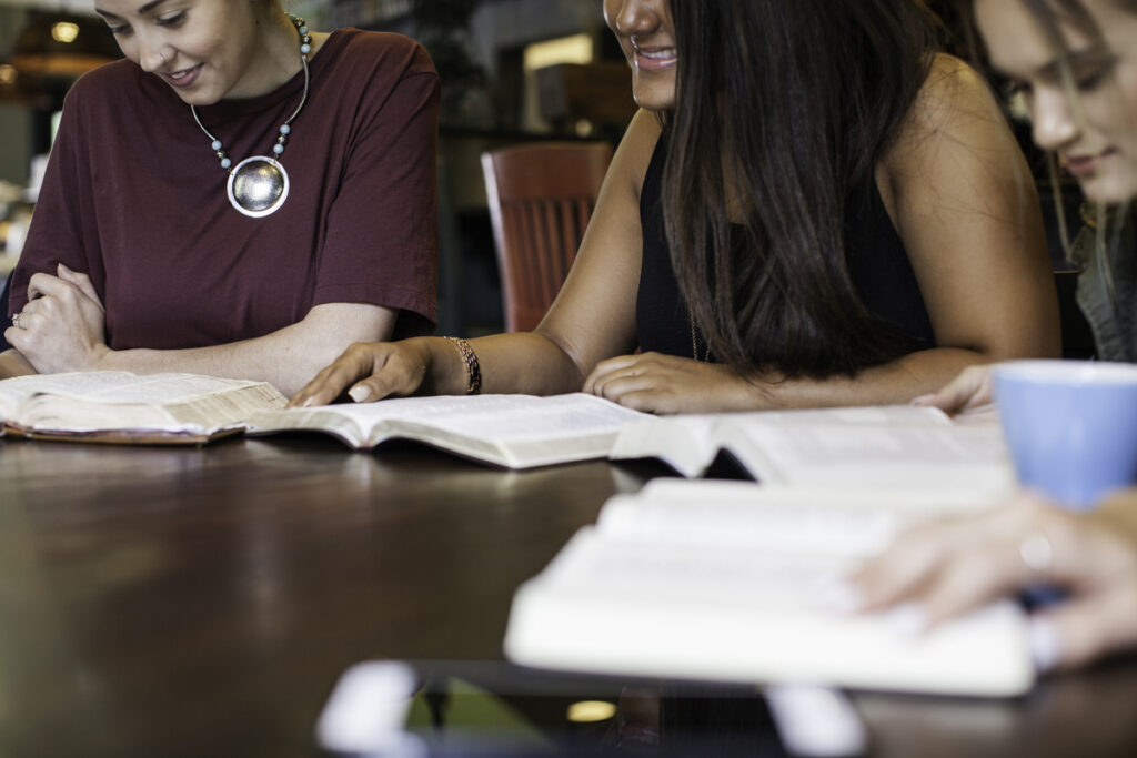 A group of Christian women engaging in a Beatitudes Bible study with open Bibles at a dining table