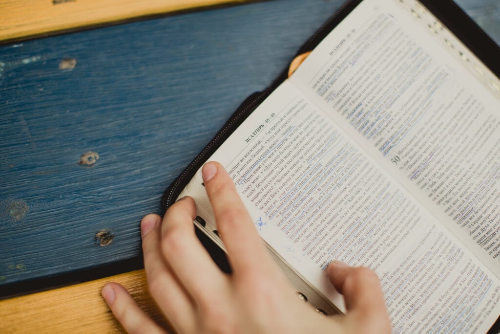 An open Bible on a blue and yellow picnic table