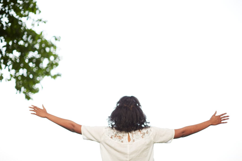 A Christian woman with her hands raised in worship because she is fully known by God