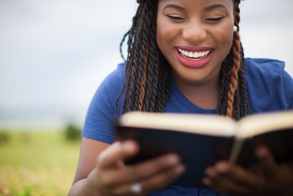 A Christian woman smiling as she reads the Bible