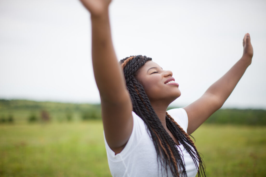 A woman with her arms raised in praise to find joy in challenging times