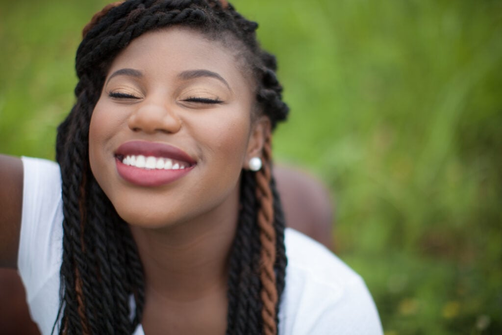 A Christian woman with eyes closed and a smile on her face because she learned how to find joy in challenging times