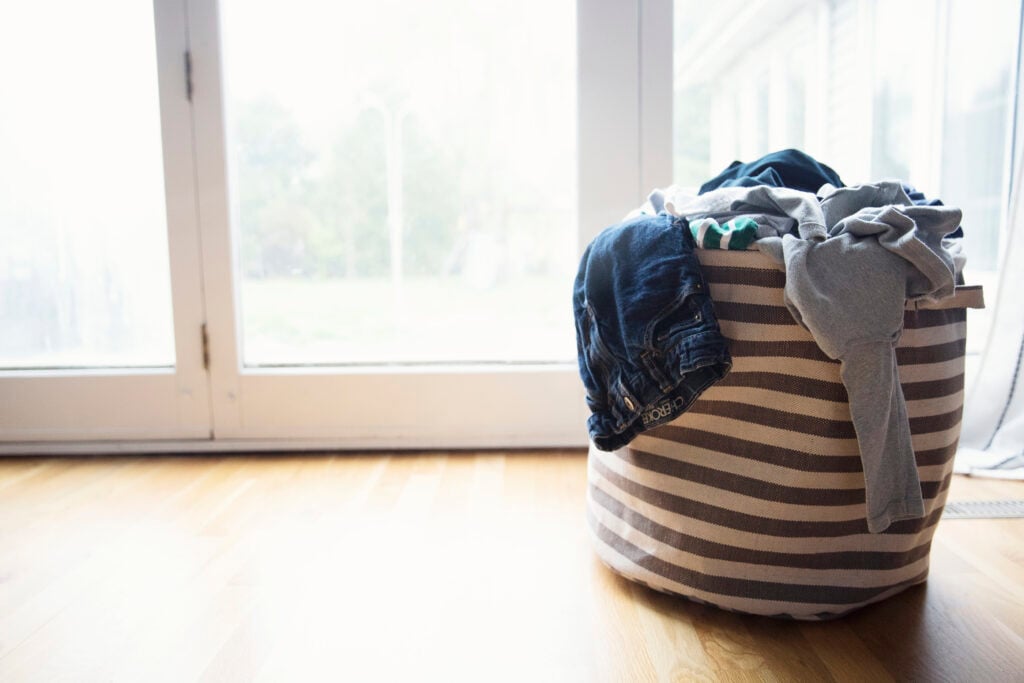Steal Your Joy 4 A grey and white striped canvas laundry hamper full of dirty laundry