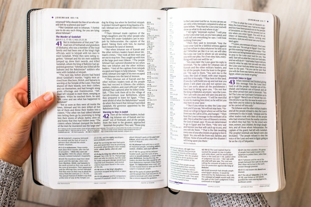 A Christian woman holding a Bible open to the book of Jeremiah as she traces the Bible's love story from Genesis to Revelation