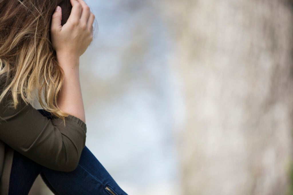 A Christian woman with her head in her hands as she struggles to endure hard times