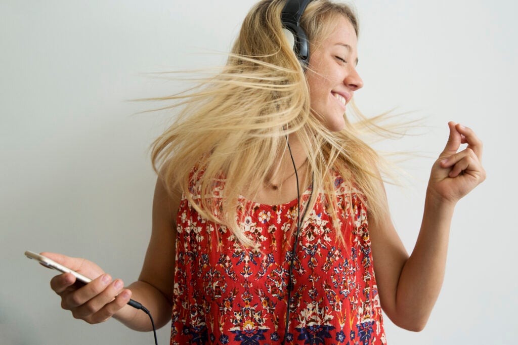 A Christian woman experiencing the power of praise to endure hard times as she snaps her fingers to the music in her headphones