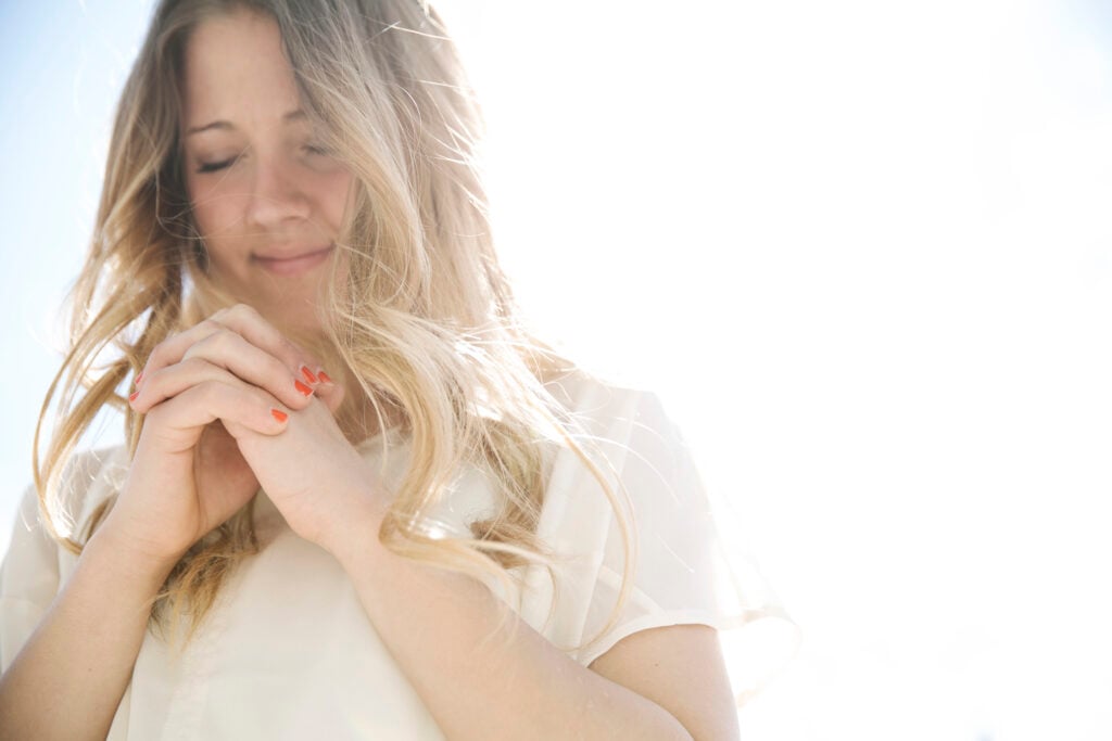 A Christian woman with her hands folded in prayer