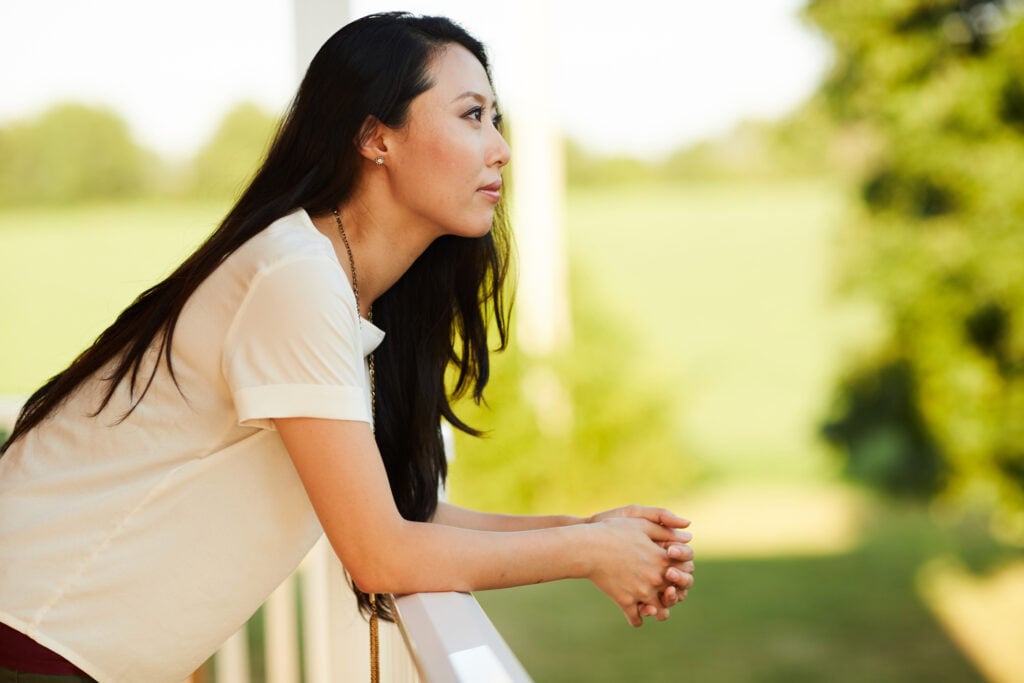 A Christian woman leaning on her porch railing, wondering how to find peace when you feel weak