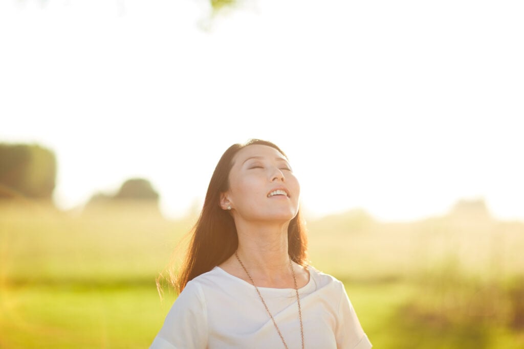A Christian woman basking in the sunlight with a smile on her face as she ponder Gideon and Jehovah Shalom
