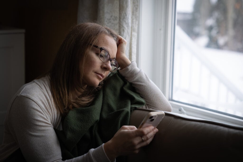 A Christian woman curled up on a couch, scrolling on her phone