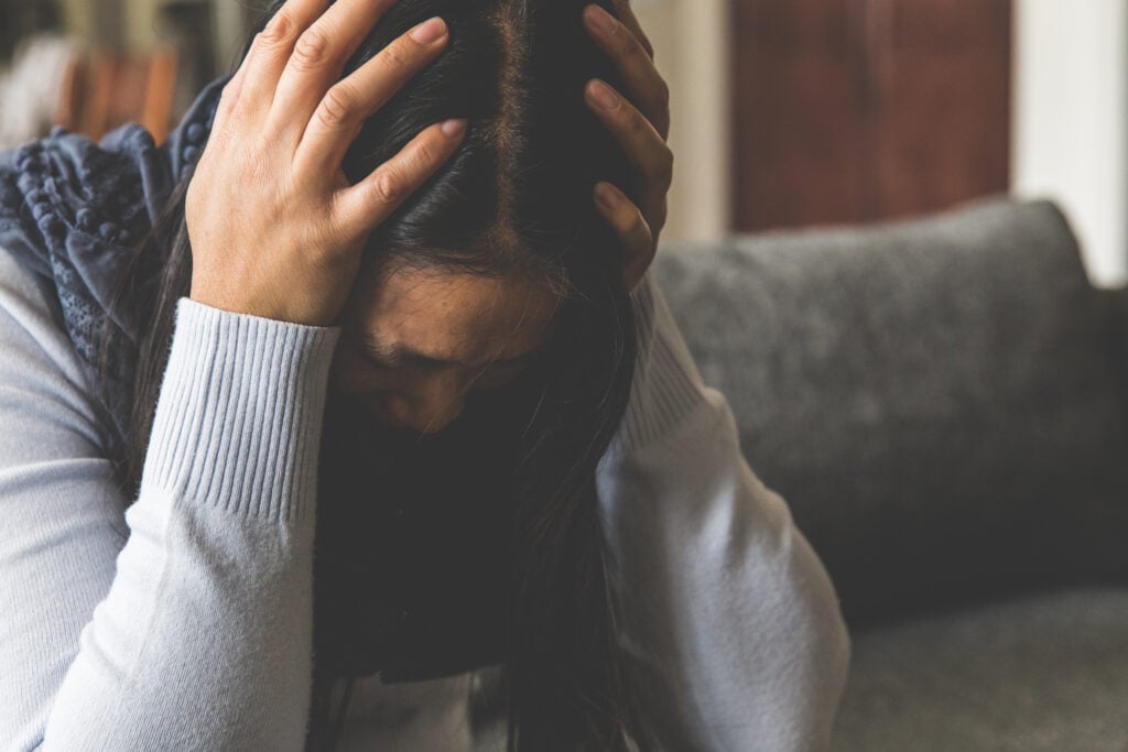 A Christian woman with her head in her hands because of anxiety