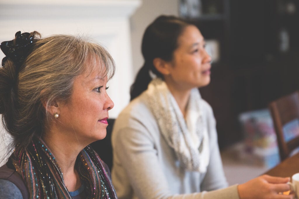 Two Christian women sitting side-by-side listening to an explanation of live at peace with everyone meaning