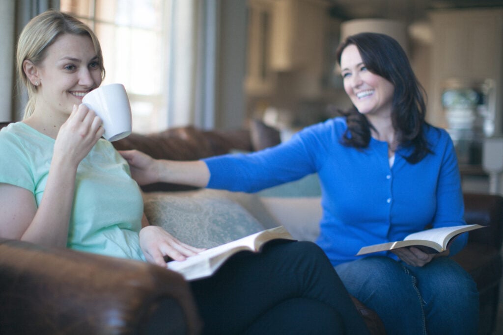 Two Christian women sitting on a couch with open Bibles to learn the difference between peacemaker vs peackeeper