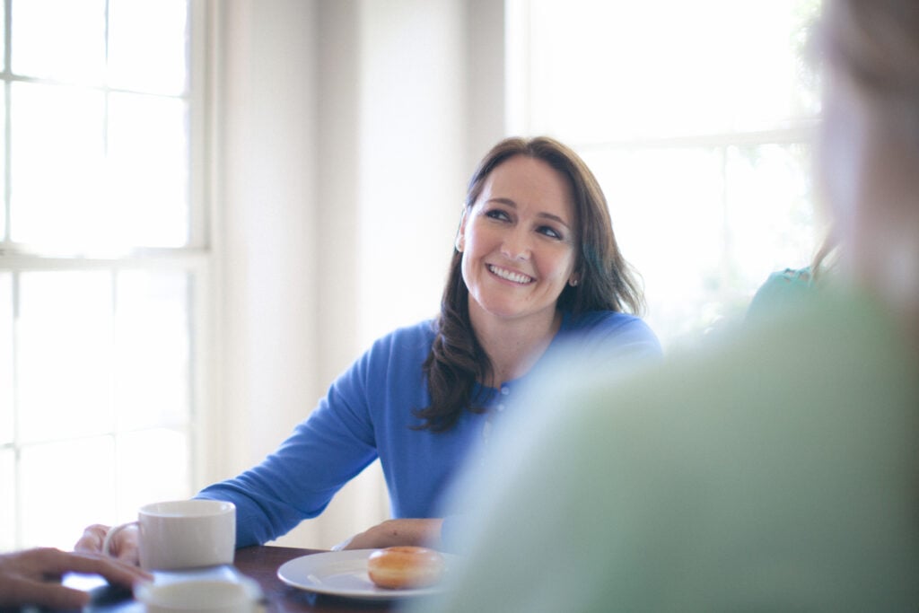 A Christian woman at a table with a group, looking at someone with a "side eye", wondering if she should be a peacemaker vs peacekeeper