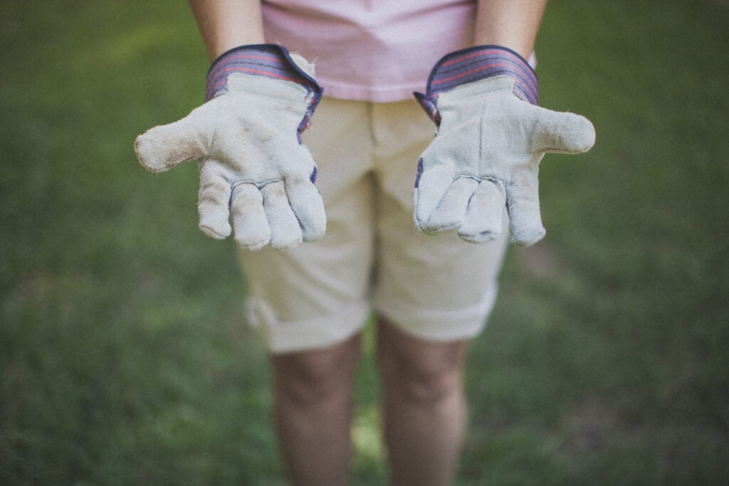 A Christian woman holding out her hands with work gloves on
