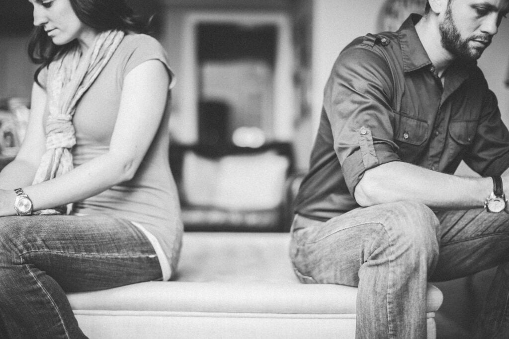 A Christian couple with their backs turned to each other, thinking about how a gentle answer turns away wrath