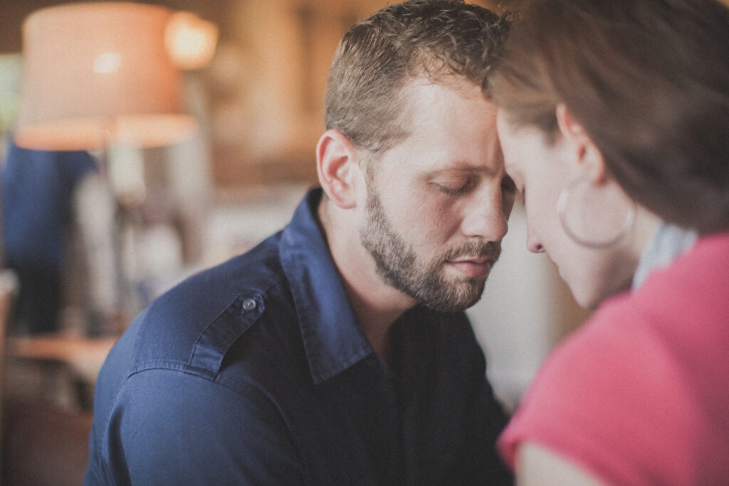 A Christian wife and husband with their foreheads touching after resolving a conflict