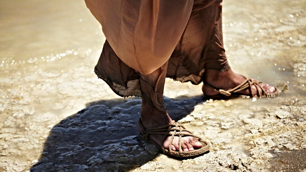 Feet wearing rope sandals, standing in water on the shore of the sea to represent God's faithfulness to the Israelites