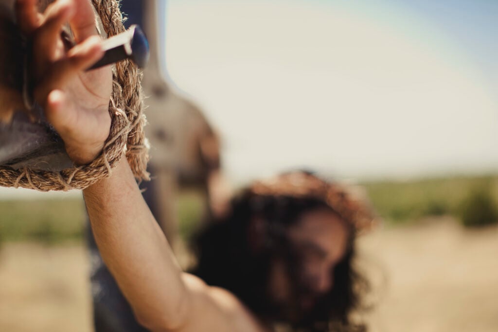 Jesus hanging on the cross, with a close-up of the nail in his palm, representing God's faithfulness