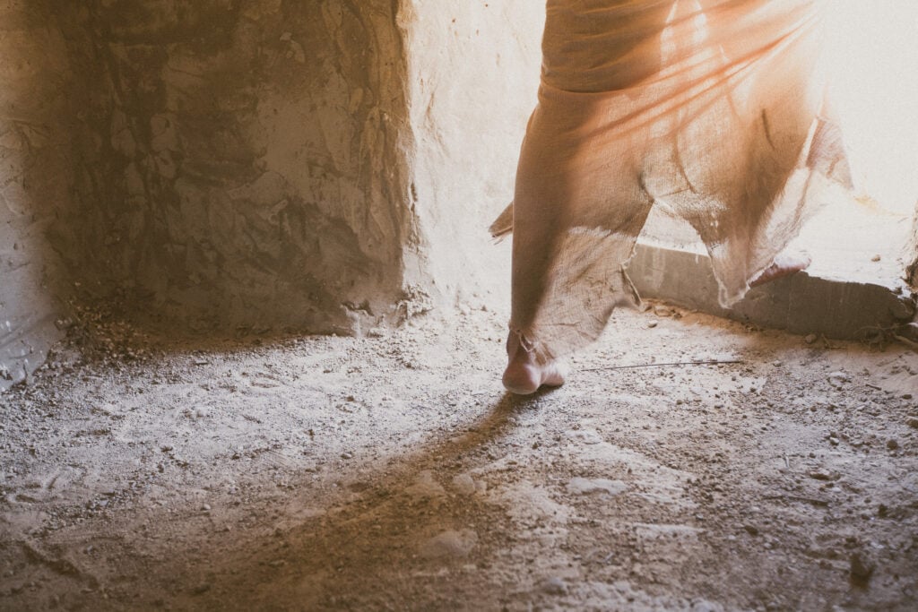 The feet of a man dressed in burial cloths, leaving a tomb, depicting Jesus' resurrection and God's faithfulness